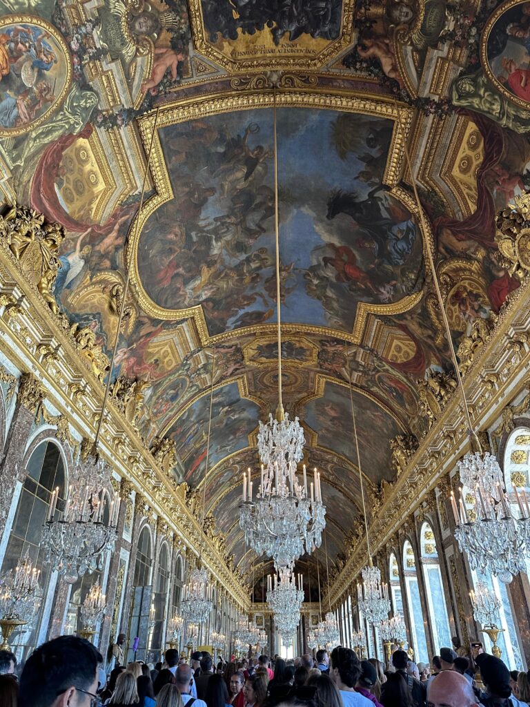 Galeria Oglinzilor Versailles, sală barocă impresionantă cu oglinzi, candelabre și lumină naturală