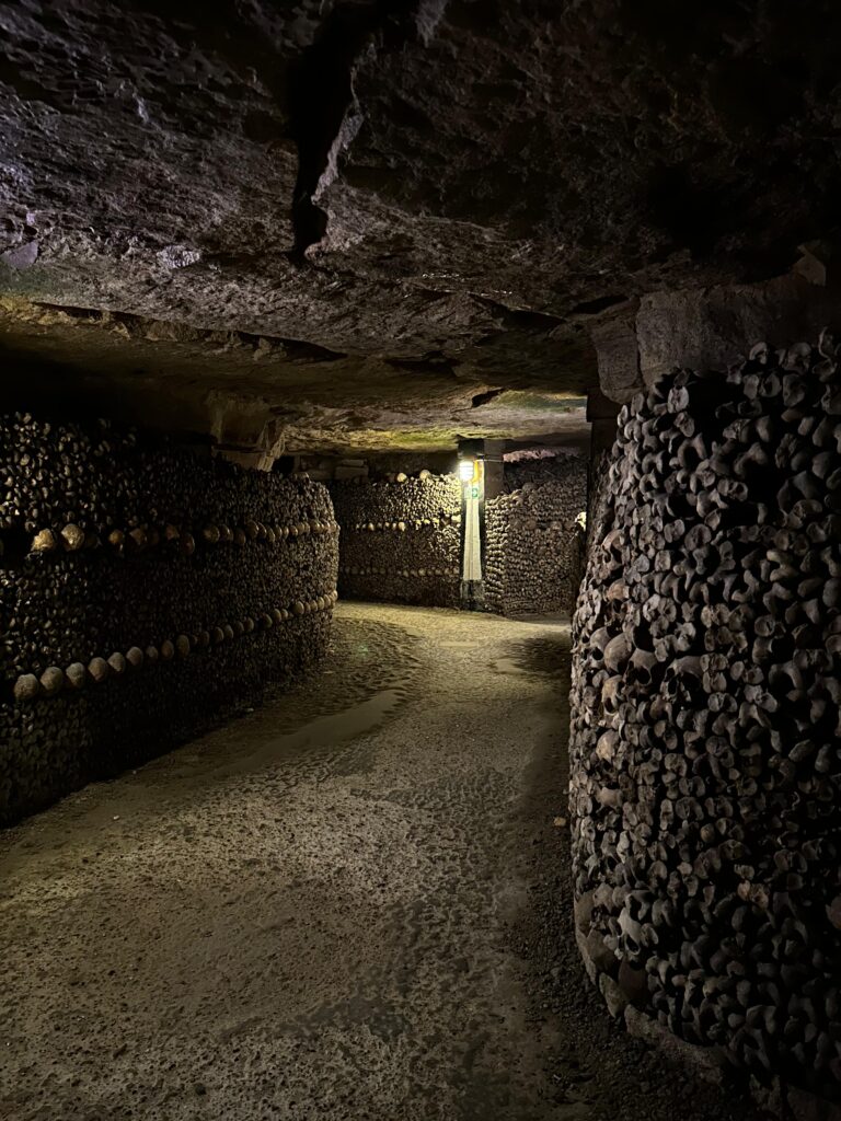 Interiorul catacombelor din Paris, osuar subteran cu coridoare întunecate și schelete