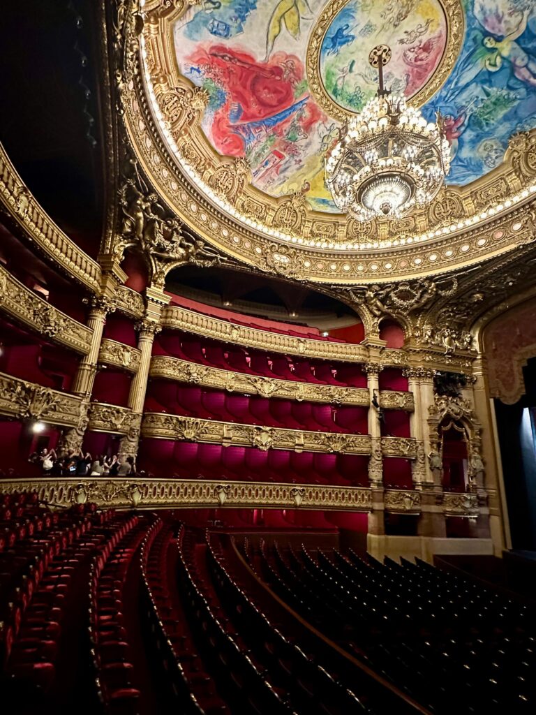 Sala de spectacole Opéra Garnier Paris, interior opulent cu candelabru monumental, loje roșii și decor baroc